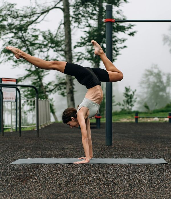 Person doing a stretching yoga pose on a mat in a park.
